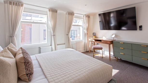 Ein Hotelzimmer mit einem großen Bett, einem Schreibtisch, einem Fernseher und einem grünen Schrank.