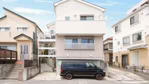 A two-story residential building with a car parked in front.
