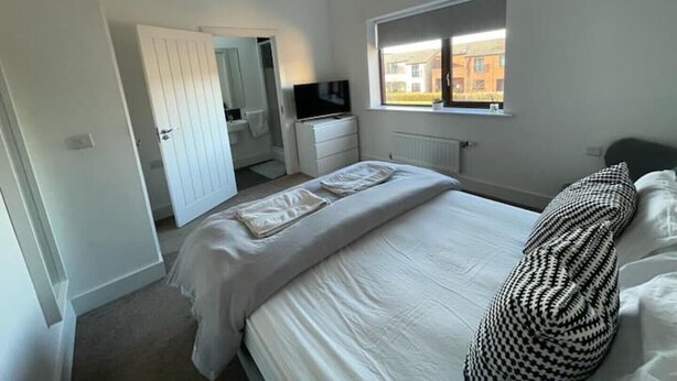 Un dormitorio con cama, televisión, ventana y puerta que da a un baño.