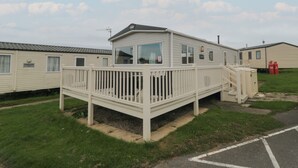 A mobile home with a deck and a small staircase leading to the entrance.
