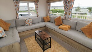 A modern living room with a grey sectional sofa, a wooden coffee table, and patterned cushions.