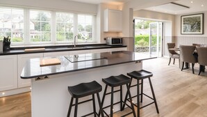 Una cocina moderna con una isla central, taburetes de bar y un comedor con sillas.