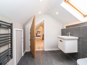 A modern bathroom with a skylight, a built-in sink, and a shower area. - The Birches (Windermere)