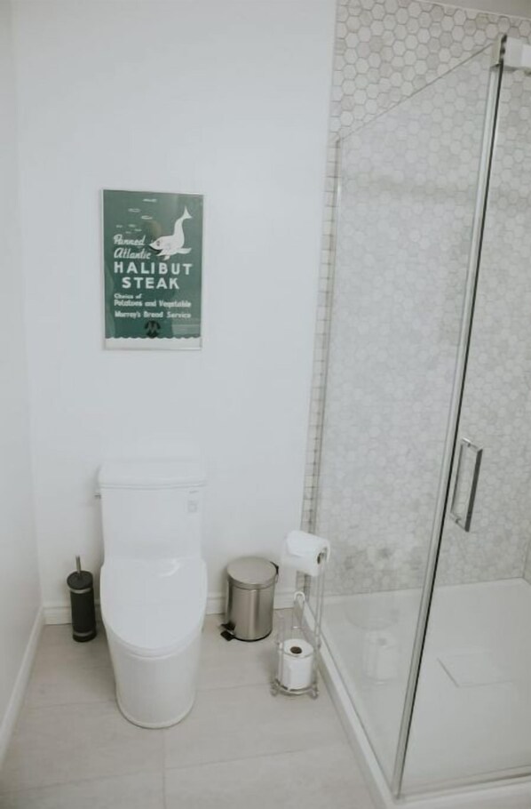 Une salle de bain équipée de toilettes, d’un bidet et d’une douche à parois de verre.