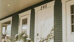 A building with a porch, numbered 295, and a row of potted plants with snow on them. - Suite n °1 au Séjour Knowlton (Knowlton)