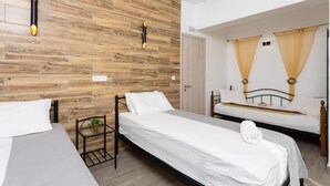 Une chambre d’hôtel avec deux lits simples, un mur en bois et une petite table sur laquelle est posée une plante.