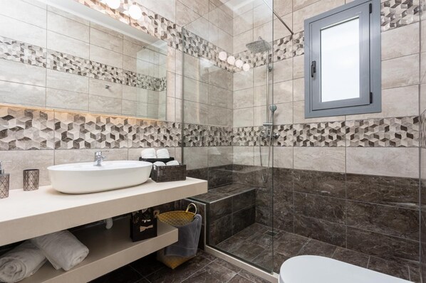 A modern bathroom with a large sink, a bathtub, and a shower area.