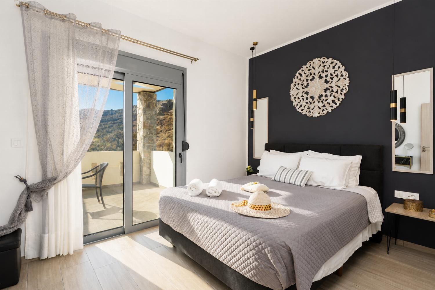 A bedroom with a bed, a balcony, a decorative wall piece, and a mirror.