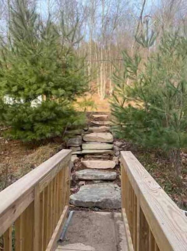 A wooden bridge with stone steps leading into a forested area.