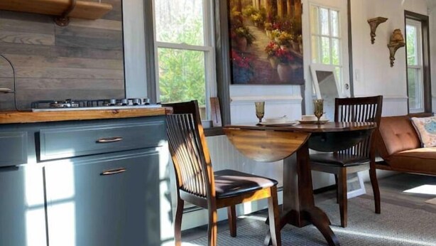 Een keuken met een houten aanrecht, een fornuis en een eethoek met twee stoelen en een tafel.