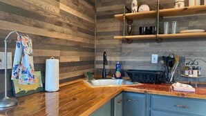Een keuken met houten wanden, een houten aanrecht, een spoelbak en kastjes.