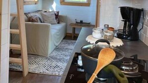 A compact kitchen with wooden beams, a small window, a sofa, and a coffee maker.