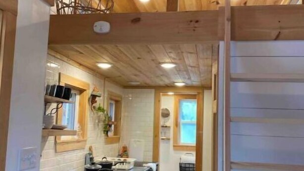 A kitchen with wooden ceiling beams, a black countertop, and a white backsplash.
