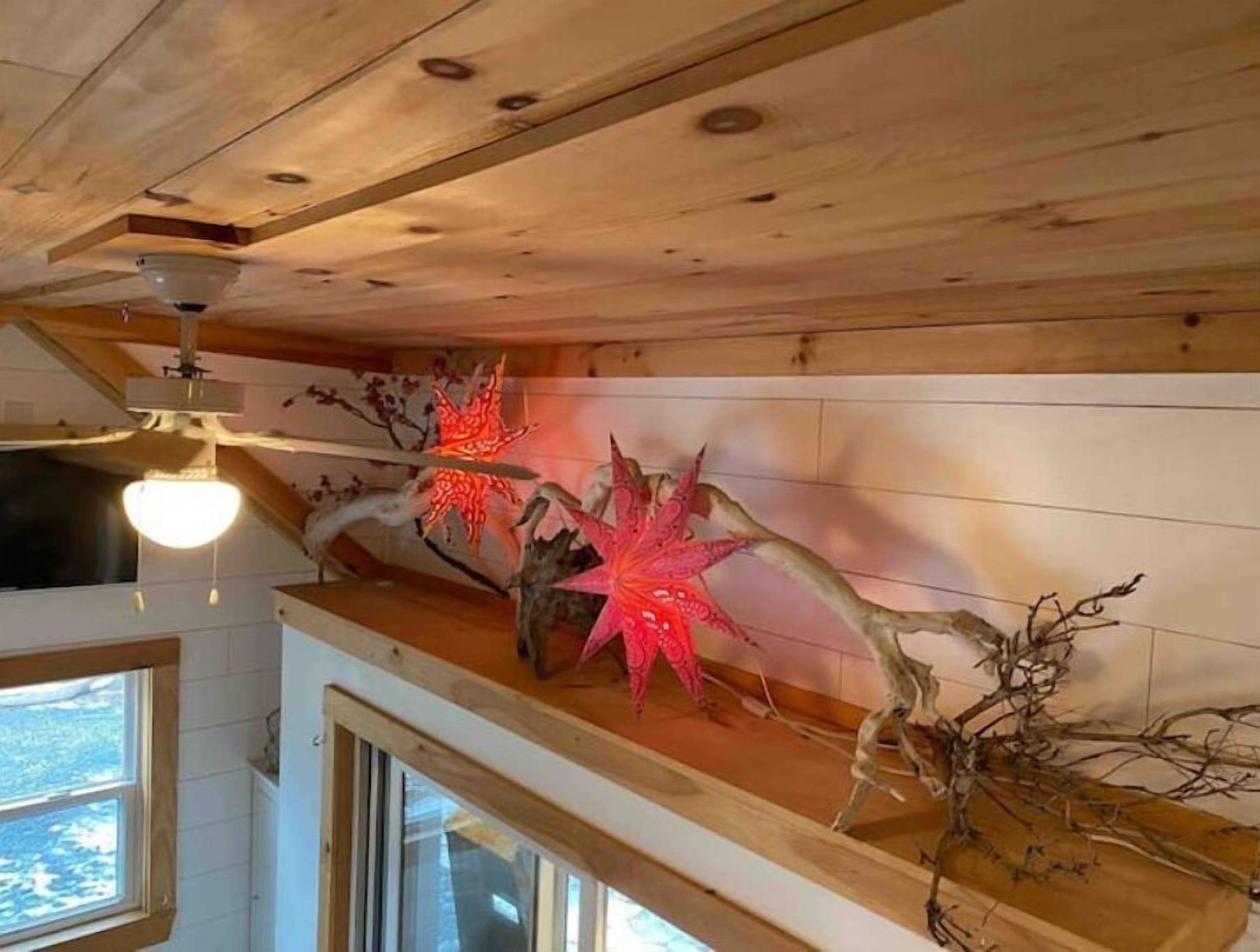 Un soffitto in legno con un lampadario a sospensione e un elemento decorativo a parete con rami e dettagli rossi.