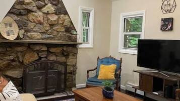 A living room with a stone fireplace, a television, a sofa, and a patterned rug.