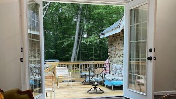 An open door leading to a deck with outdoor furniture and a stone wall.