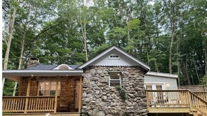 A rustic cabin with a stone exterior, wooden deck, and a small porch.
