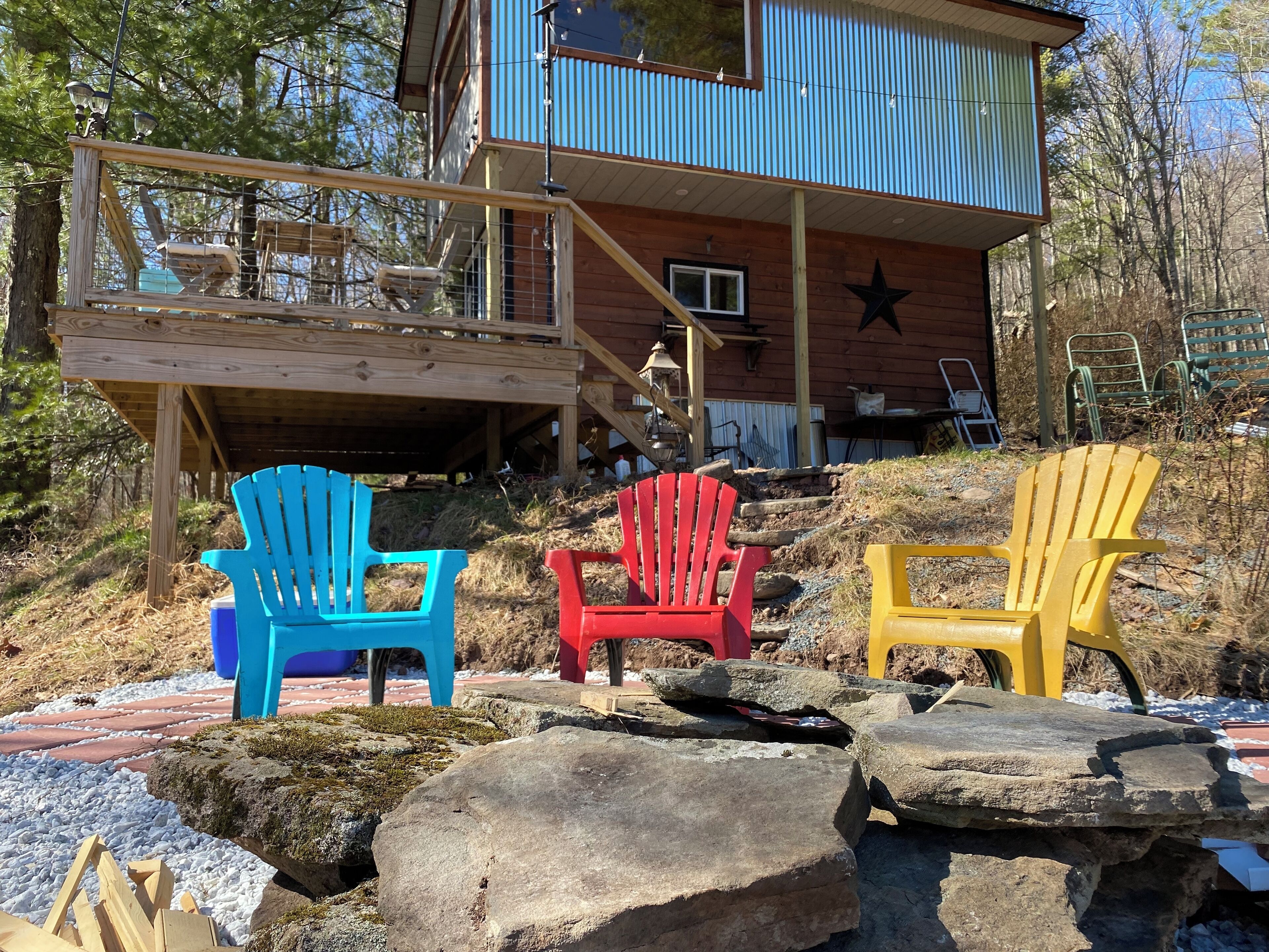 Une cabane avec une terrasse, des fauteuils Adirondack aux couleurs vives et une étoile sur le bâtiment.