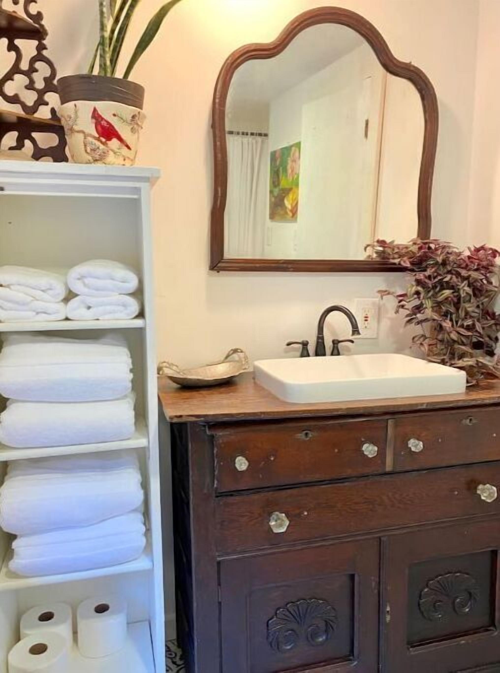 Un baño con toallero blanco, lavamanos blanco y espejo con marco decorativo.