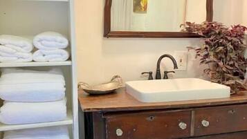 Un baño con toallero blanco, lavamanos blanco y espejo con marco decorativo.