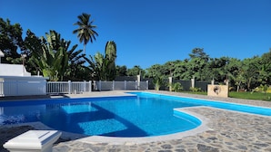 A swimming pool with a stone deck, surrounded by palm trees and a white fence. - Apartment for 4 with large pool



 (Samaná)