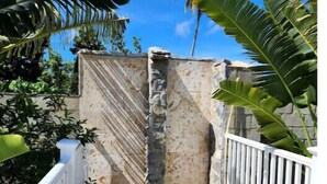 A stone pathway leading to a stone wall with a white fence on either side, surrounded by tropical foliage. - Apartment for 4 with large pool



 (Samaná)