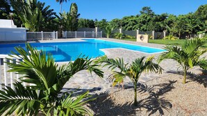 A swimming pool surrounded by palm trees and a white fence. - Large apartment w/pool very close to the beach

 (Samaná)