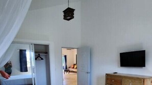 A bedroom with a bed, a wooden dresser, a television, and a door leading to another room. - Large apartment w/pool very close to the beach

 (Samaná)