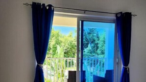 Ein Zimmer mit einer Schiebetür und einem Ausgang zu einem Balkon mit Stuhl und Tisch.