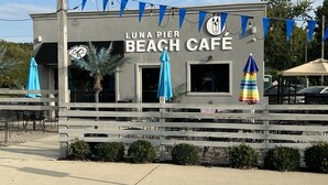 A Luna Pier Beach Cafe with a simple facade, outdoor seating, and a wooden fence. - Lakeside Oasis - Lake Erie Lakefront with Golf Cart (Luna Pier)