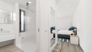 A modern bedroom with a bed, bedside table, lamp, and a view of the bathroom. - Villa Paraíso - Holiday Villa with Private Pool By SCH (São Martinho do Porto)