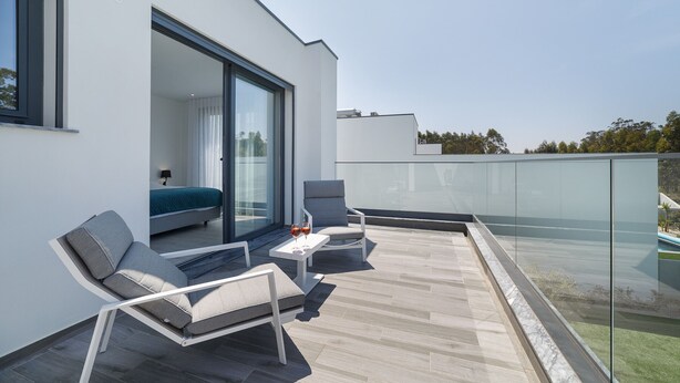 A modern outdoor balcony with a sofa, chairs, and a table, overlooking a pool and greenery. - Villa Paraíso - Holiday Villa with Private Pool By SCH (São Martinho do Porto)