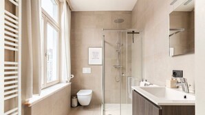 Een moderne badkamer met een douchecabine van glas, een toilet en een wastafel met spiegel.