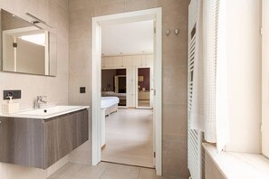 A modern bathroom with a large mirror, a sink, and a shower area.