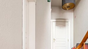 Un corridoio con pavimento in legno, una porta bianca e una scala con ringhiere in legno.