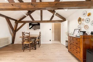 A dining area with a wooden table and chairs, a TV mounted on the wall, and a reception desk with a sign.