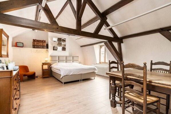 A bedroom with a bed, a wooden chair, a table, and a dresser.