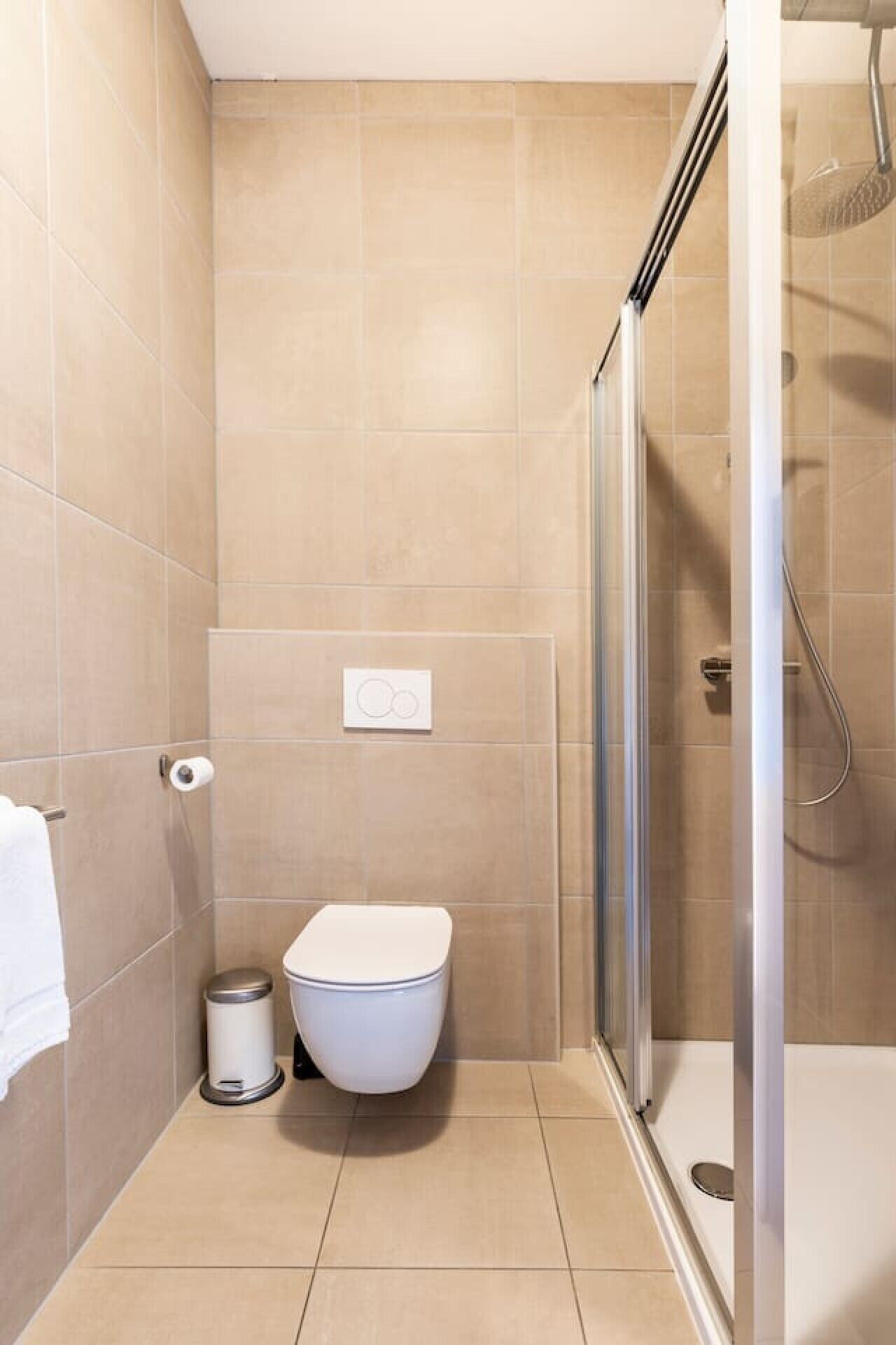 Ein Badezimmer mit Toilette, Mülleimer und einer Duschkabine.