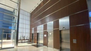 A modern lobby with a glass entrance, a wooden reception desk, and three elevators. - Puerto Madero Piso 20 Vista al Rio  (Buenos Aires)