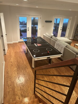A room with a pool table, a sofa, and a staircase.