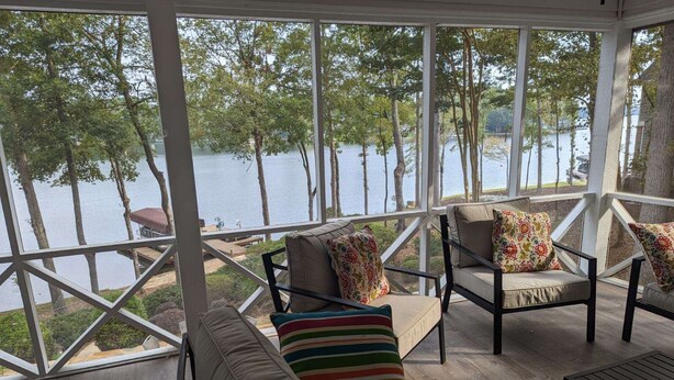 A covered outdoor seating area with a view of a lake and trees. - Lakefront Home for Spring and Summer Getaways! (Eatonton)