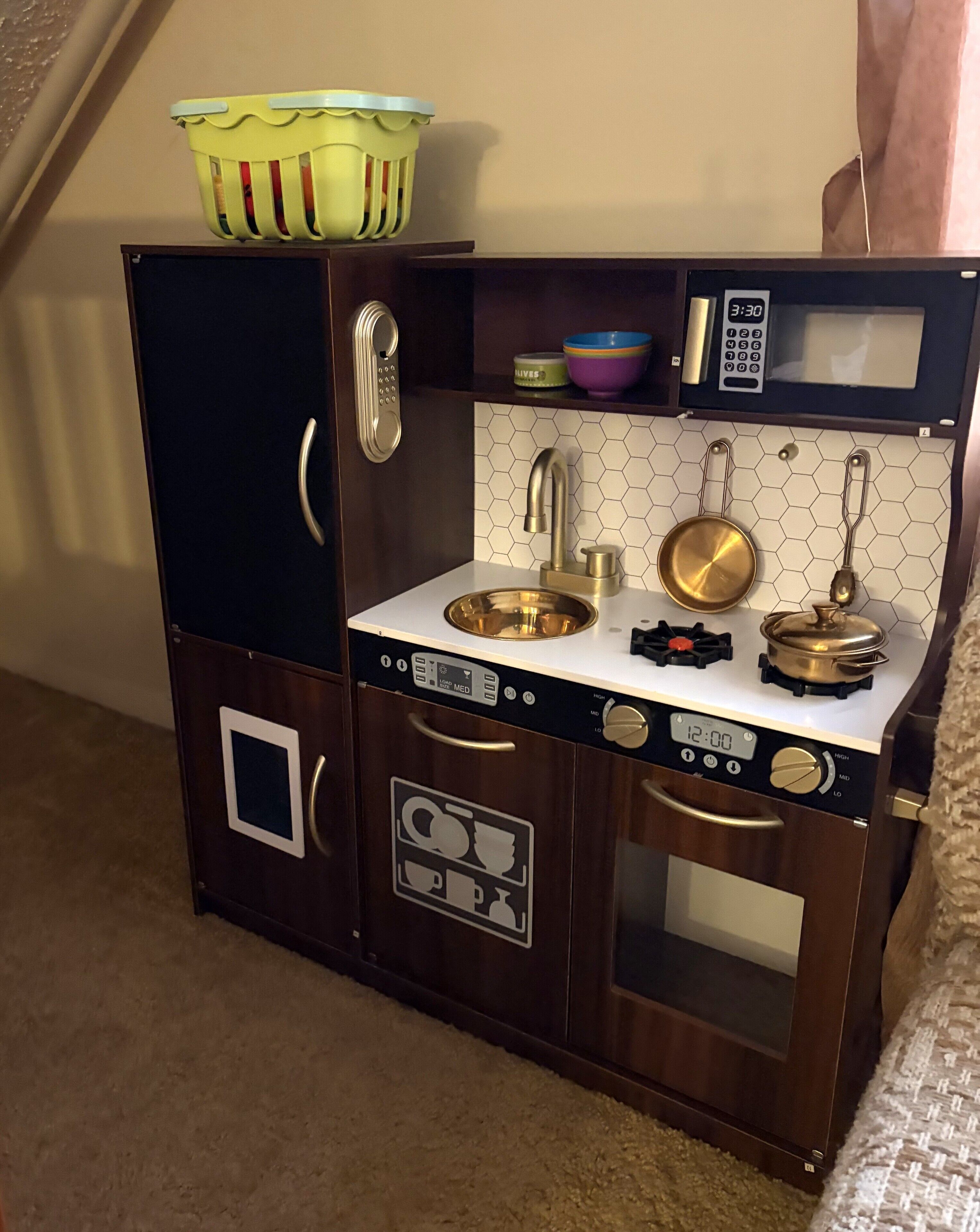 A toy kitchen with a sink, stove, and storage cabinets.