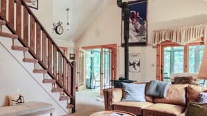 Un salon spacieux avec un escalier en bois, un canapé en cuir et une table basse ronde.