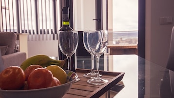 Uma mesa com uma garrafa, dois copos e uma tigela de frutas.