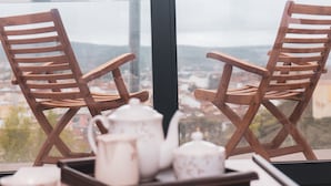 Two wooden chairs facing a window with a tray of white teacups and a teapot. - Alojamientos VEN, Vista Extremadura Norte (Plasencia)
