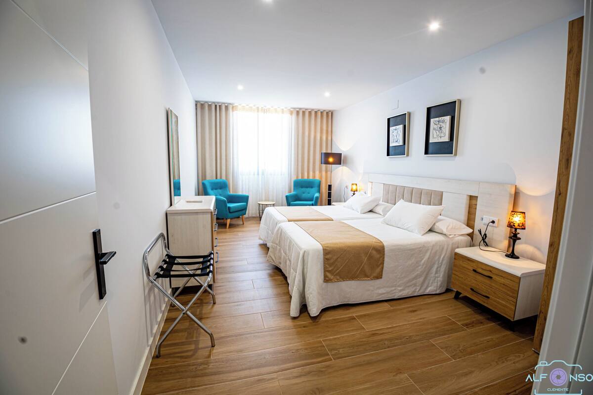 A modern hotel room with a bed, bedside tables, a desk, and a chair.
