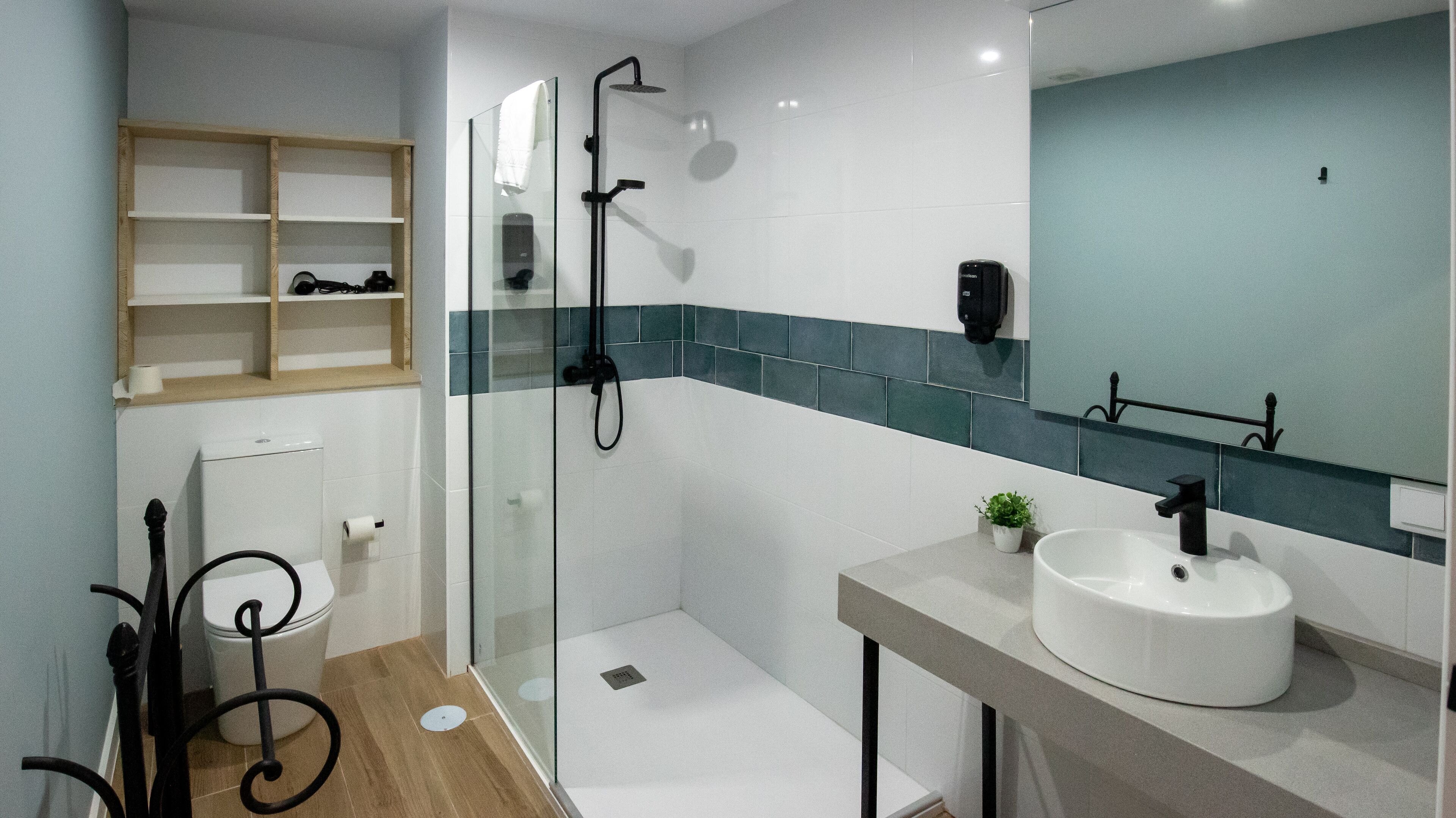 Un baño moderno con ducha de vidrio, lavamanos blanco y espejo sobre él.