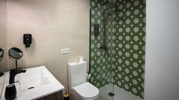 A bathroom with a white sink, a toilet, and a shower with green star-patterned tiles. - Alojamientos VEN, Vista Extremadura Norte (Plasencia)
