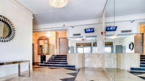 En rummelig lobby med et geometrisk gulvmønster, en trappe og en moderne receptionsdisk.