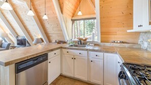 A modern kitchen with wooden beams, a dishwasher, cabinets, and a stove. - Pet Friendly with Big Views! (Tahoe City)